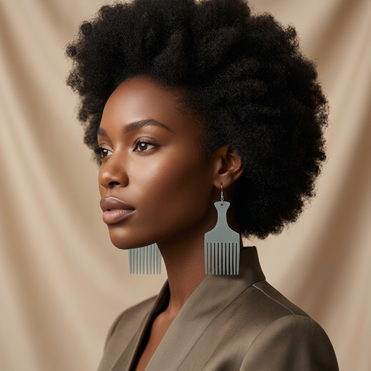 Model with a natural afro hairstyle wearing Mist Grey Heritage Comb Earrings in sage grey-green, paired with an olive blazer, against a draped beige backdrop.