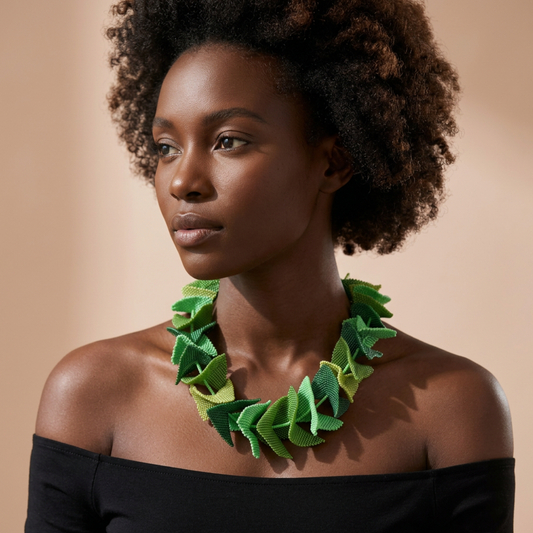 Model wearing the Butterfly Beaded Necklace in shades of green pointed leaf-like petal beaded segments, against a beige backdrop.