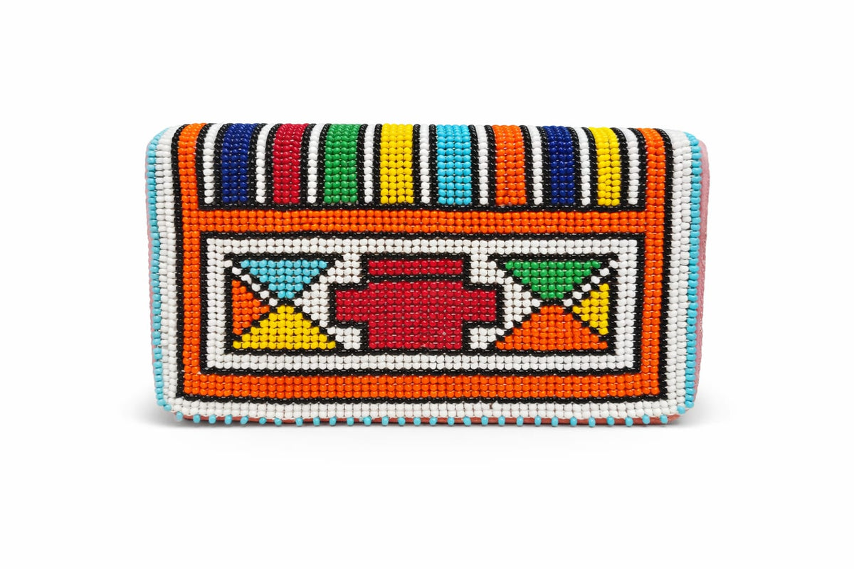 Product shot of the Ndebele Beaded Clutch on a white background, showing the multicolour geometric beadwork pattern with striped border and central red, white and orange motif.