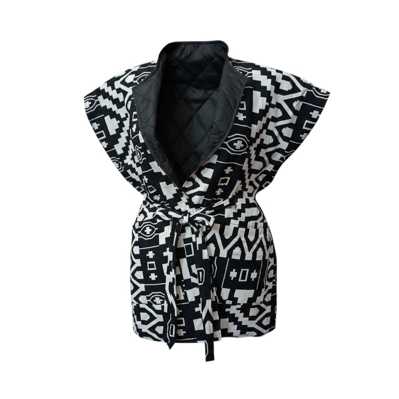 Flat lay product shot of the Reversible African Geometric Body Warmer on a white background, showing the wide shoulder shape, open shawl collar with black quilted lining and front tie-belt.
