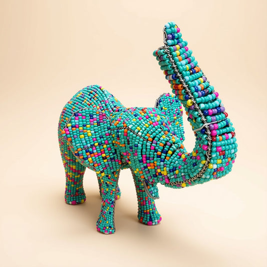 Product shot of the Beaded Safari Elephant sculpture against a plain beige background, showing the teal and multicolour beadwork detail on the body, ears, legs and raised trunk.