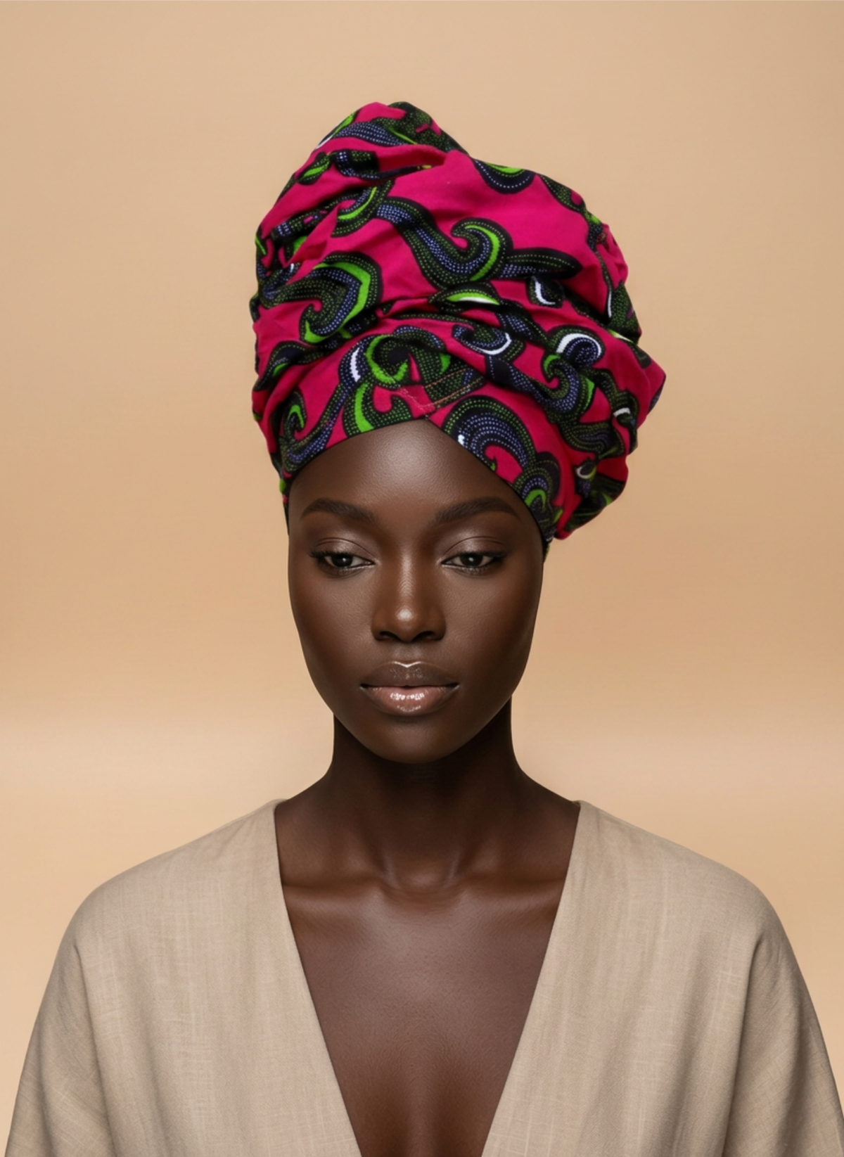 Model wearing the Pink Bloom ready-to-wear African headwrap in bright pink with green, navy and white swirl pattern, against a plain beige background.