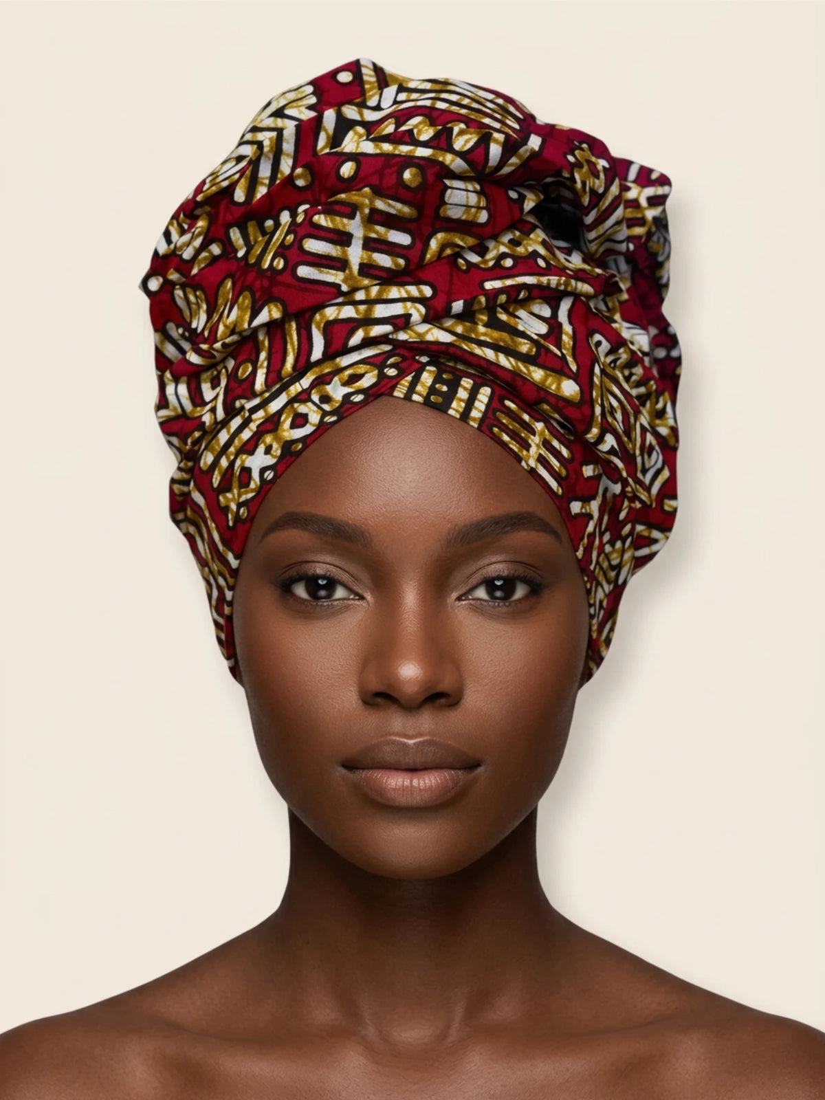 Tinkers traditional African print head wrap in red, white, and gold geometric patterns on a mannequin head.