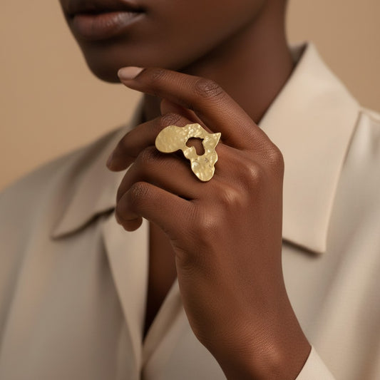 Tinkers oversized brass ring featuring a textured Africa-shaped disc worn on a model's finger.