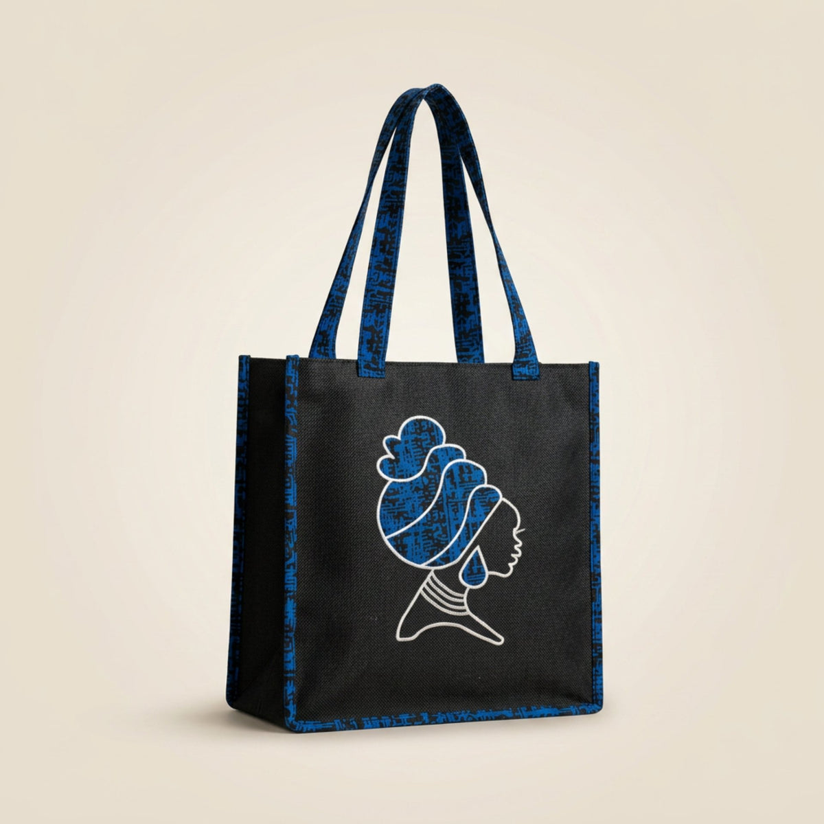 Tinkers black fabric tote bag featuring a white embroidered silhouette of a woman with a headwrap and blue patterned straps