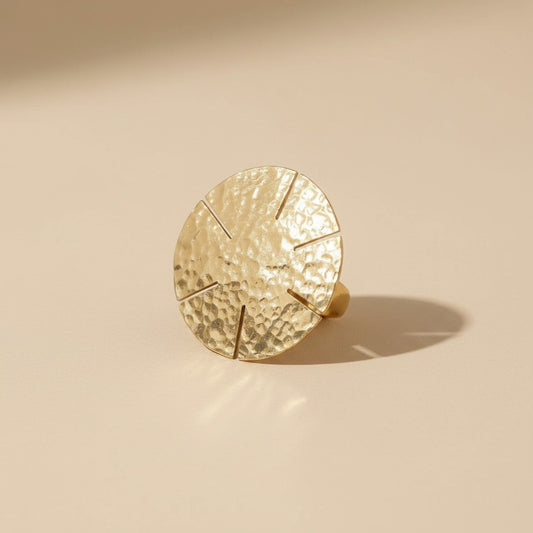 Tinkers hammered brass statement ring featuring a large sun-ray disc with geometric cuts on a textured surface.