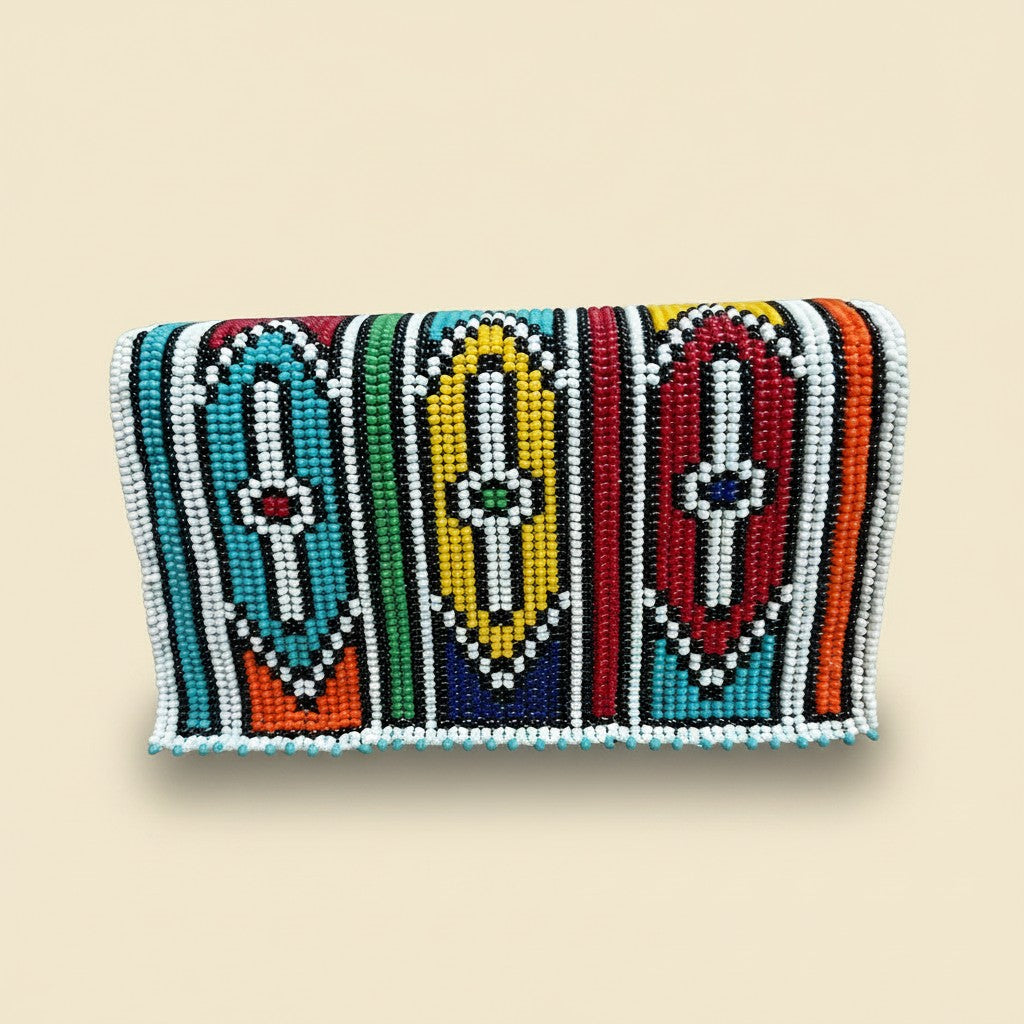 Tinkers handcrafted beaded clutch featuring three vibrant Ndebele doll figures in turquoise, yellow, and red beads.